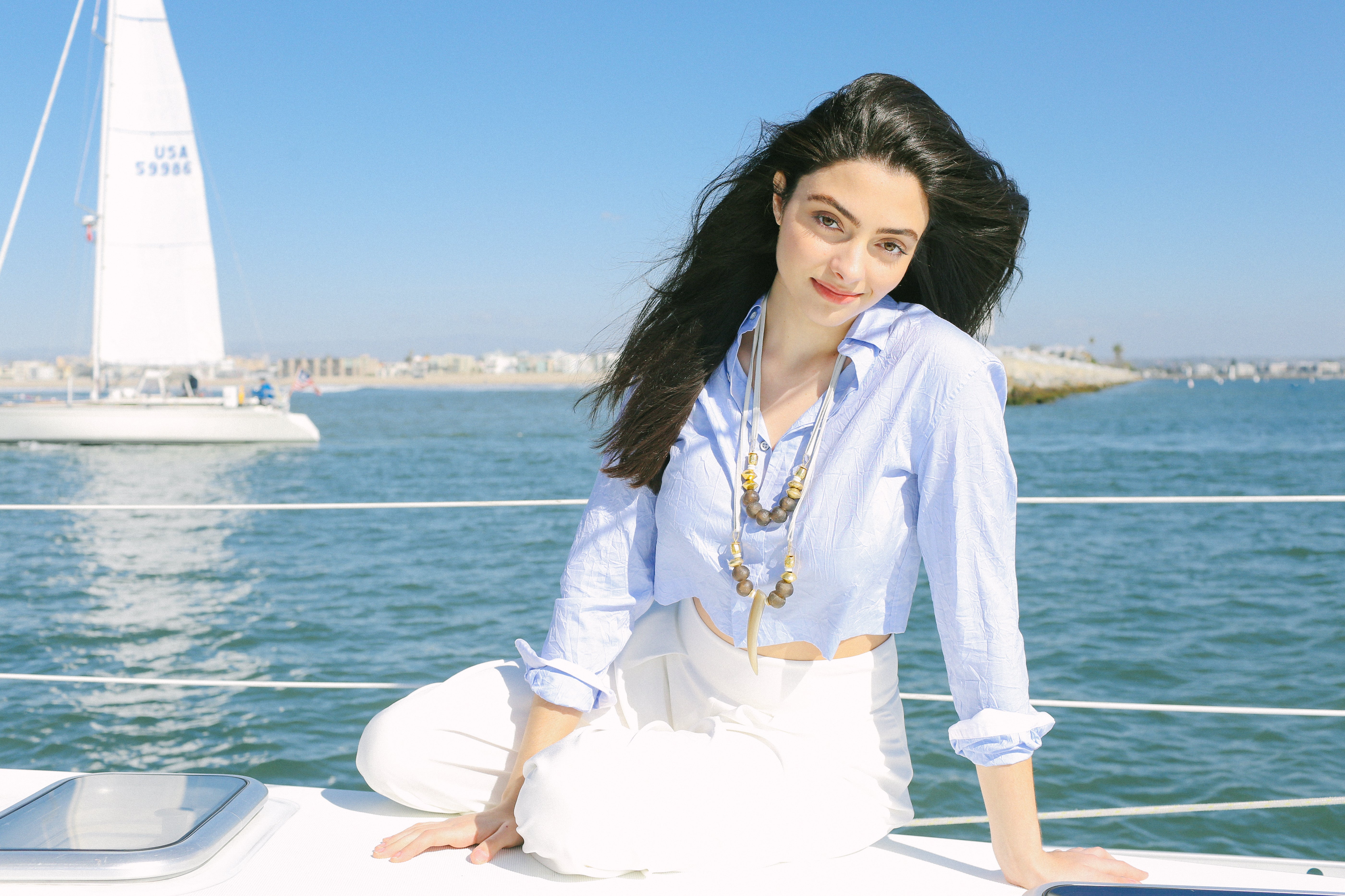 Model wearing Akola horn and bead necklace on a sailboat